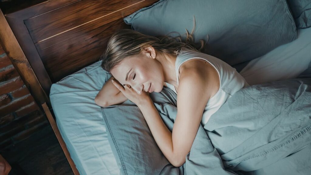 Femme allongée dans son lit, se reposant sous une couette bleue